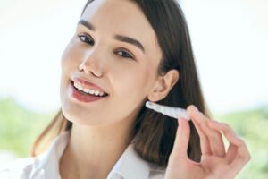 smiling-woman-holding-aligner-for-perfect-dental-c-2026-01-08-22-10-35-utc - Phelps and Cohen Orthodontics