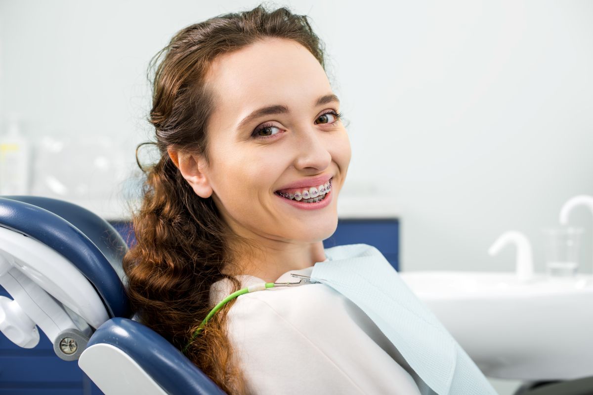 Smiling woman with braces in a dental chair at a clinic, looking at the camera